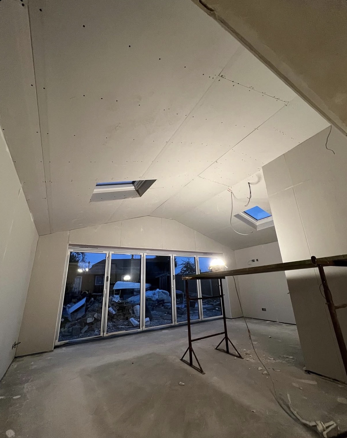 Extension interior fitted with plasterboard around roof lights and bifold doors