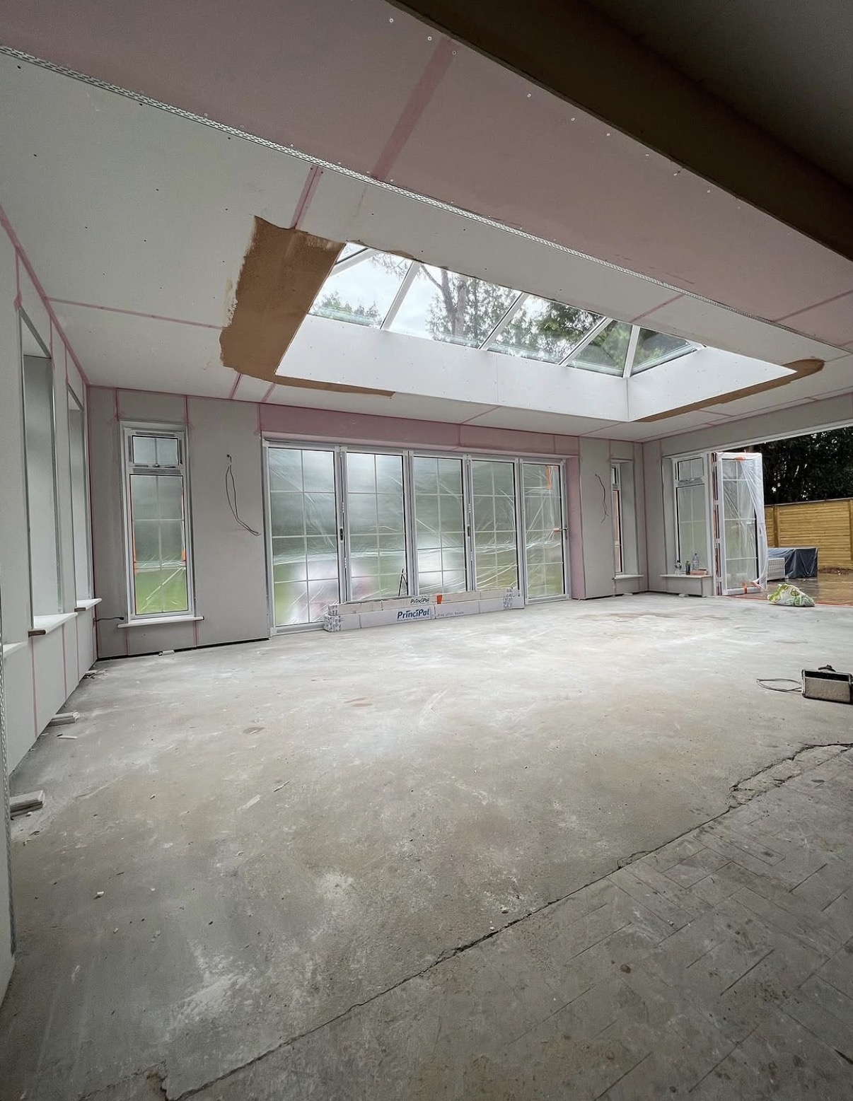 Large extension fitted with plasterboard and dry lining around a roof lantern and bifold doors